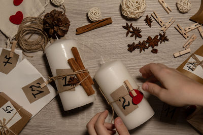 Cropped hand of woman holding christmas decoration on table