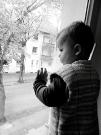 Side view of boy standing by tree