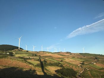 Wind turbines on field against sky