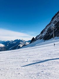 Scenic view of snowcapped mountains against blue sky