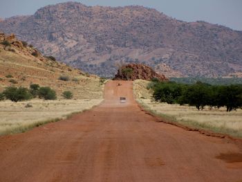 Dirt road amidst mountains against sky