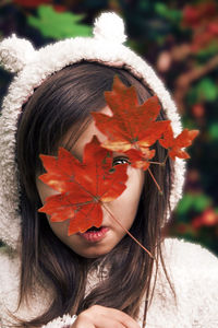 Close-up portrait of woman with autumn leaves