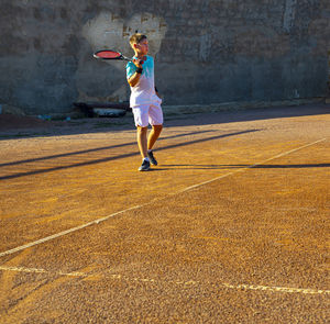 Boy teenager tennis player on a clay court. there is a heart on the wall. professional tennis   