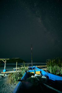 Boats moored on land against sky at night