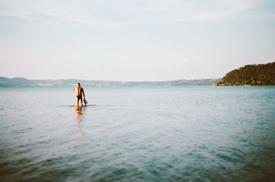 Man standing in sea against sky