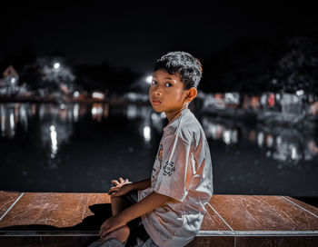 Side view of young man standing against lake