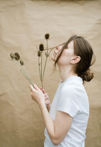 Woman holding flowers on beige background