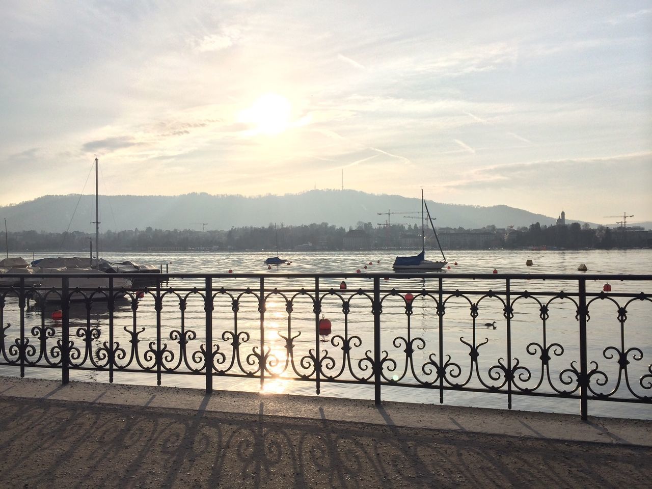 water, sky, railing, sunset, sun, river, cloud - sky, transportation, mountain, sunlight, lake, tranquility, scenics, sunbeam, tranquil scene, nature, beauty in nature, pier, mode of transport, sea