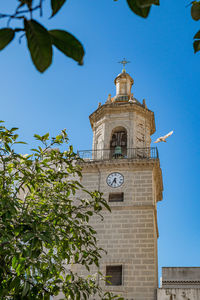 Low angle view of clock tower amidst buildings against sky