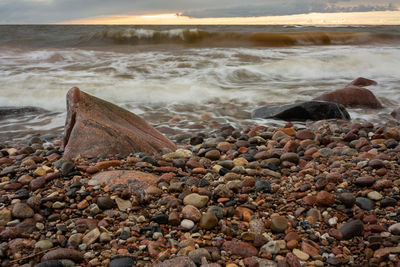 Rocks on shore at beach during sunset