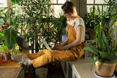 Side view of woman sitting on potted plant