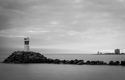 Lighthouse by sea against sky at dusk