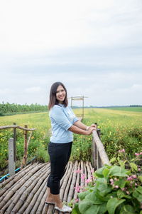 Portrait of smiling woman standing on footpath against landscape