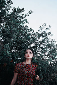 Portrait of beautiful young woman against trees