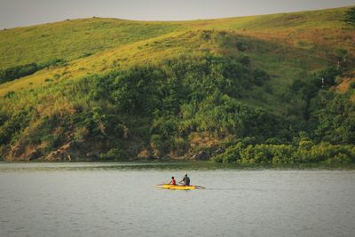 Man sitting on riverbank against sky