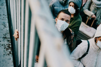 Portrait of man wearing mask standing by railing