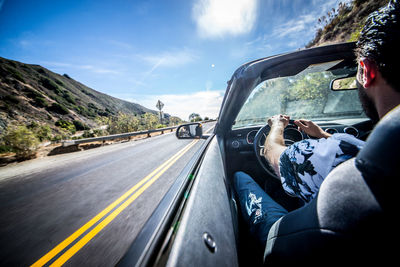 Rear view of man driving car on road