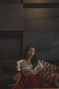 Portrait of a young woman sitting on wall at home