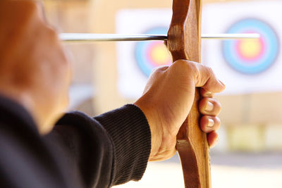 Close-up of man with bow and arrow aiming at target