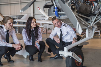 Engineer showing airplane wheel to trainees in hangar