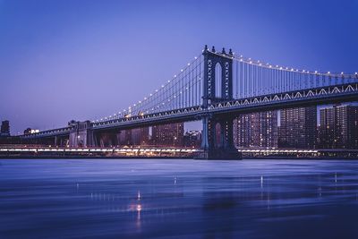 Illuminated bridge against clear sky at night