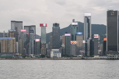 Sea by modern buildings against sky in city