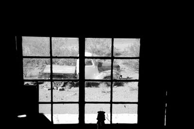 Silhouette person looking through window in building