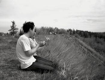 Side view of man sitting on field