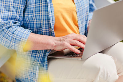 Unrecognizable senior woman using laptop for distance learning outdoors