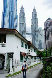 Woman walking on pathway against built structures