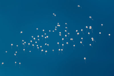 Low angle view of balloons flying against clear blue sky