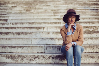 Young man looking away while sitting on staircase