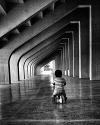 Boy sitting on toy bicycle in building