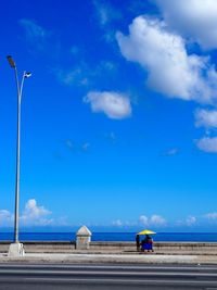 People on road against blue sky