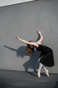 Full length of woman dancing against wall
