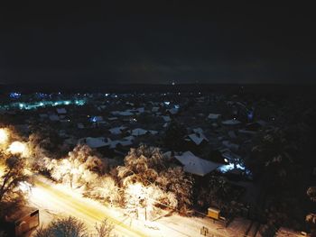 Aerial view of illuminated beach against sky at night