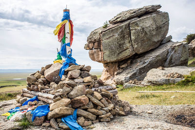 Low angle view of stack of rocks on field against sky