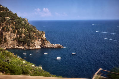 High angle view of sailboats by sea against blue sky