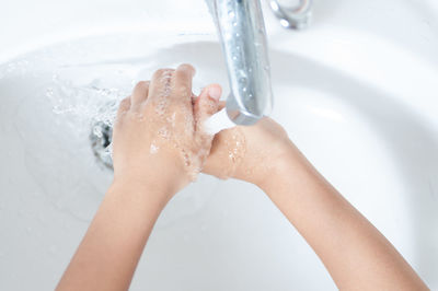 Close-up of person washing hands under faucet