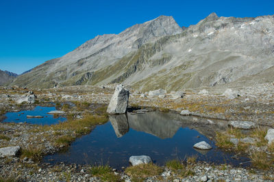 Scenic view of sea and mountains against clear blue sky