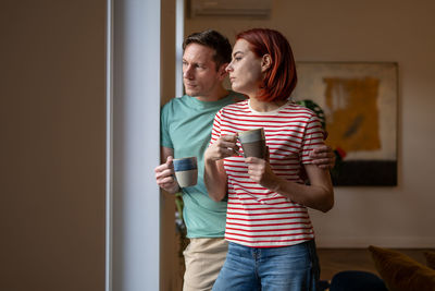 Side view of young woman standing against wall