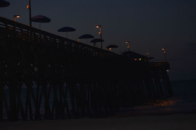 Illuminated street lights against sky at night