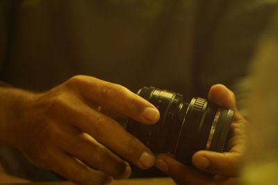 Close-up of human hands holding camera lens