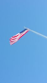 Low angle view of american flag against clear blue sky