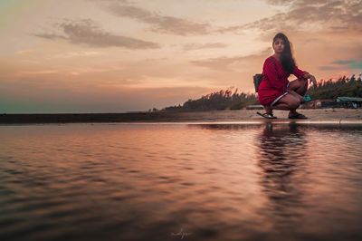 Woman on sea against sky during sunset