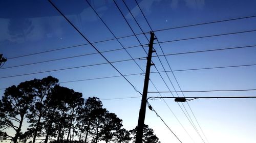 Low angle view of silhouette electricity pylon against sky