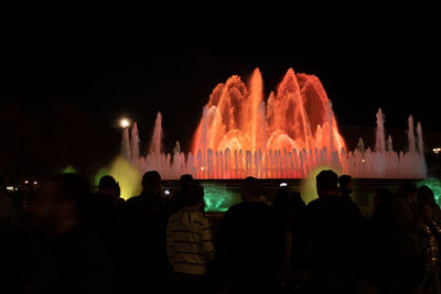 Rear view of people at music concert against sky at night