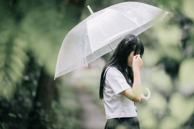 Woman with umbrella standing on wet rainy day