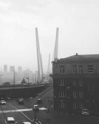 Vehicles on road by buildings against sky in city