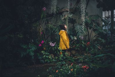 Side view of woman standing amidst plants